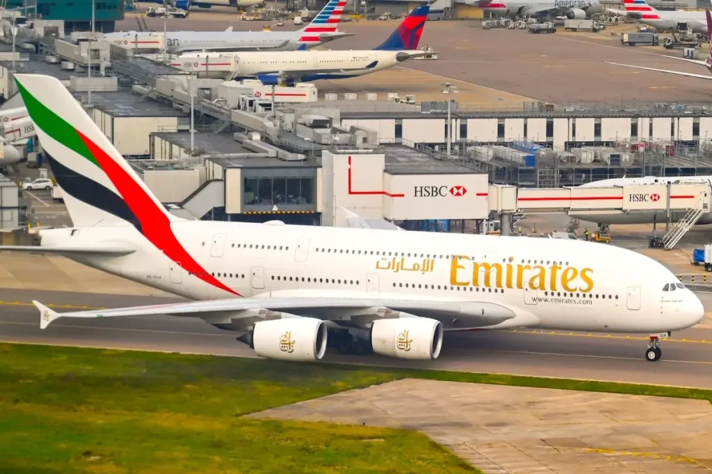 LONDON, ENGLAND - NOVEMBER 2018: Airbus A380 super jumbo jet operated by Emirates taxiing for take off at London Heathrow Airport. In the background are jets parked at Terminal 3