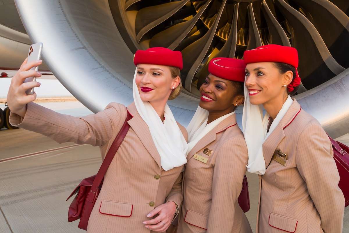 Smiling flight attendants taking selfie. Emirates airline cabin crew members